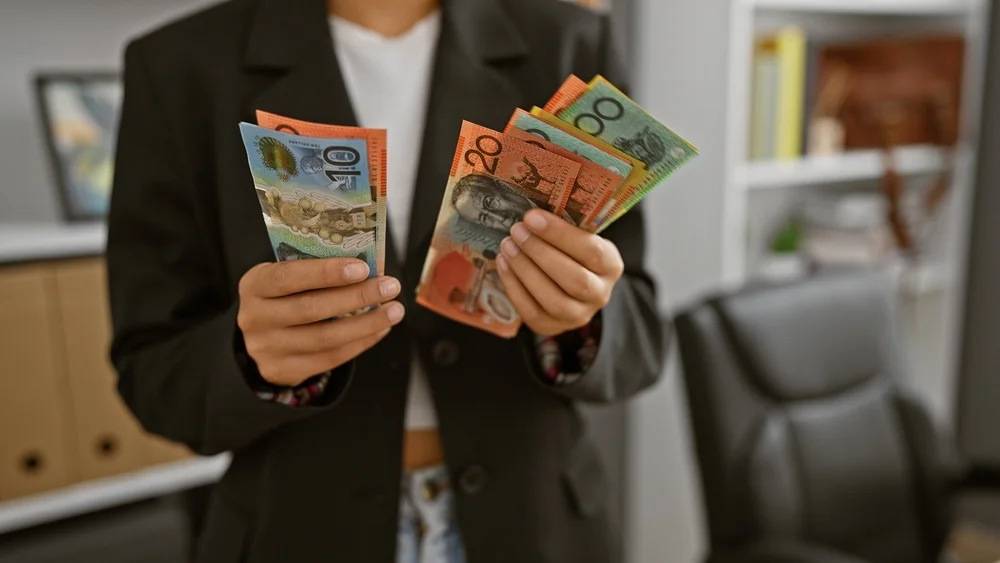 Person in business attire counting Australian banknotes indoors
