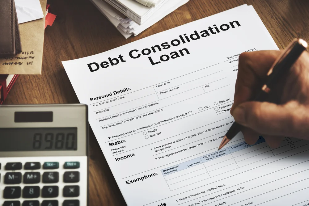 Person filling out a debt consolidation loan application form beside a calculator
