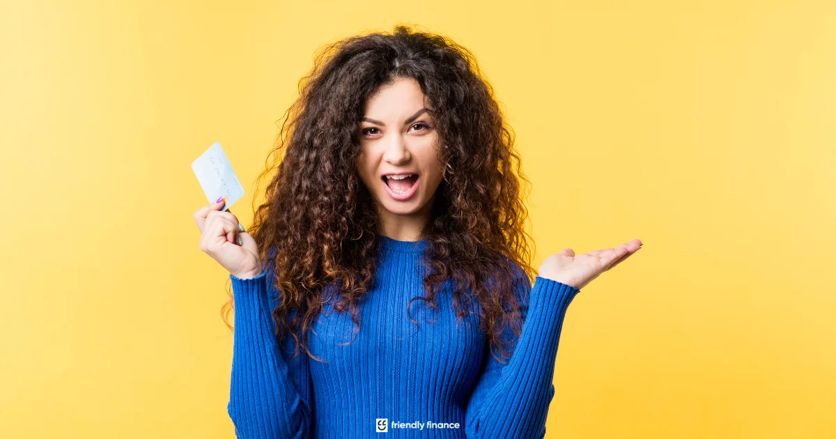 A woman with curly hair makes a frustrated or shocked expression at the camera while holding up a credit card against a bright yellow background.