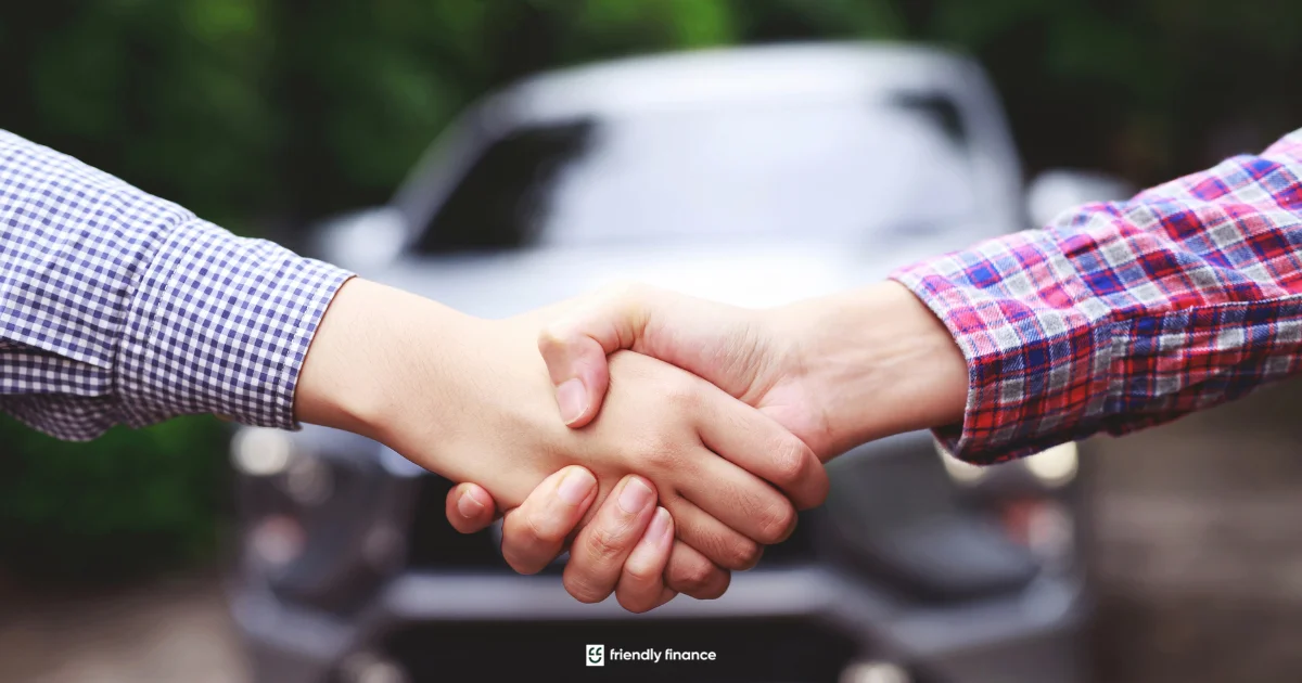 A close-up of two people shaking hands to signify an agreement, with the front of a silver car out of focus in the background.