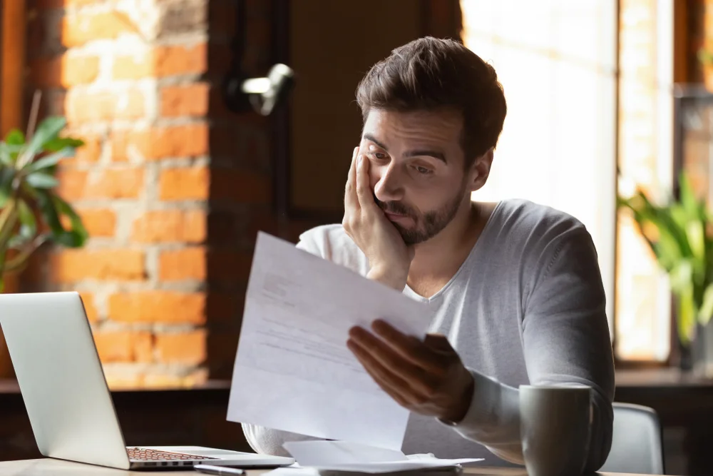 Worried man reviewing financial documents at home