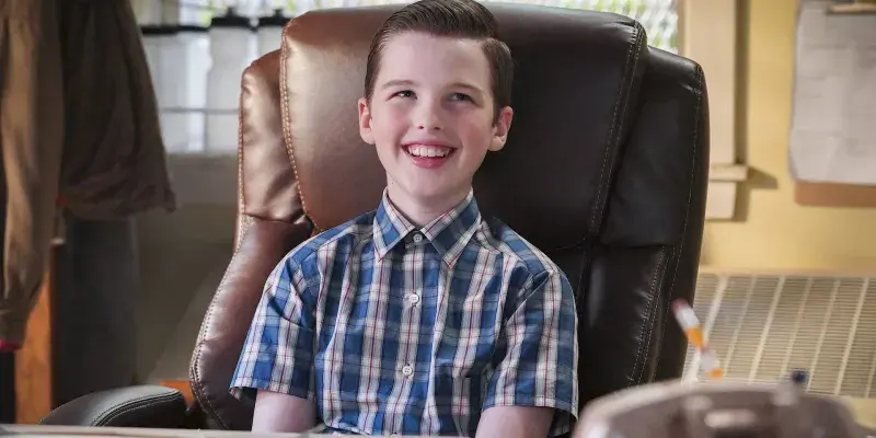 Smiling young boy in a plaid shirt sitting in a large leather office chair