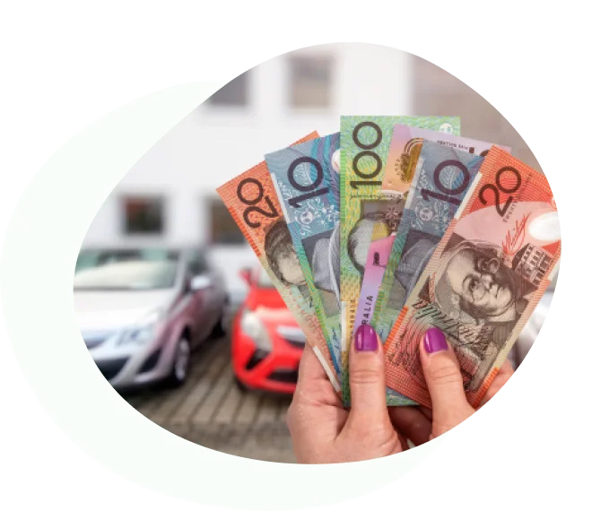 Person holding Australian banknotes in front of parked cars
