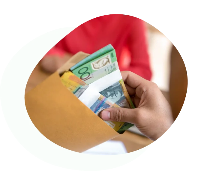 Hand placing Australian banknotes into a brown envelope
